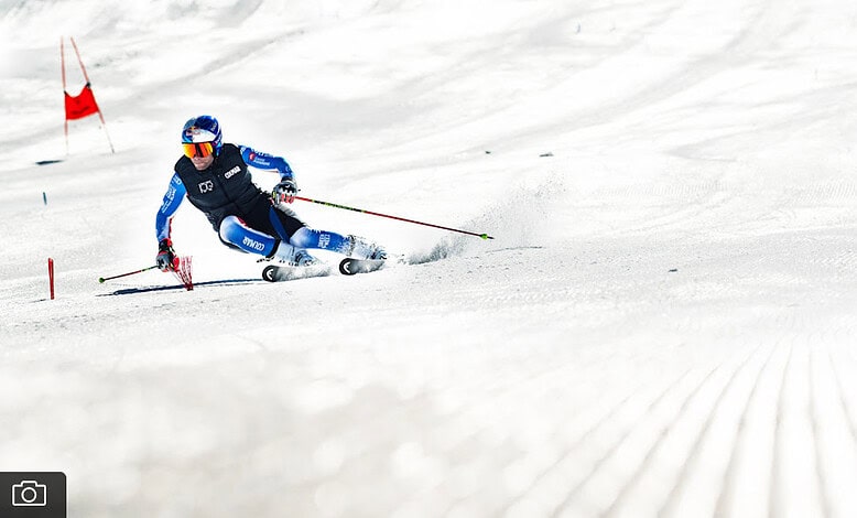 Skiing enthusiast carving through fresh snow on a sunny winter day, emphasising winter sports and outdoor adventure.