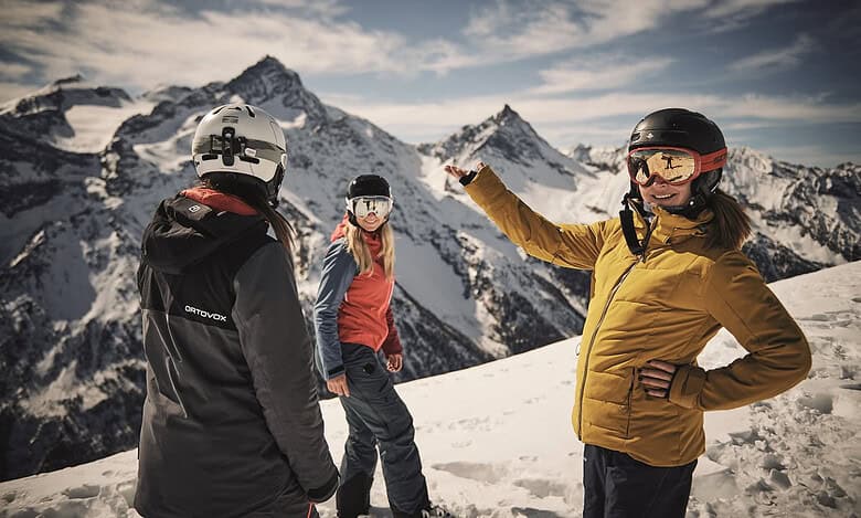 Exploring winter sports in snowy mountains with smiling skiers in helmets and jackets.