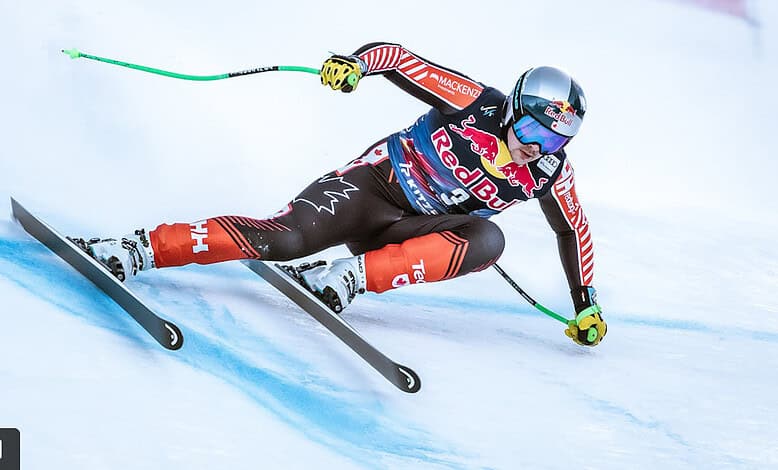 High-speed alpine skier in Red Bull gear making a sharp turn on snowy slope during winter sports competition.