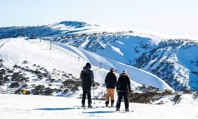 Bright winter landscape with three skiers heading towards snowy mountain slopes, showcasing the best in winter outdoor activities and winter sports.