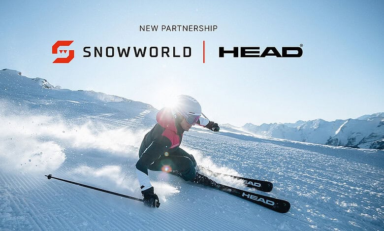A skier in a red jacket and helmet carving through fresh snow on an indoor ski slope, showcasing HEAD's latest ski equipment in collaboration with SnowWorld Group.
