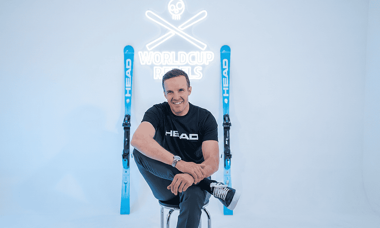 A comfortable man sitting with skis and poles in a winter studio, promoting winter sports gear and accessories for winter enthusiasts.