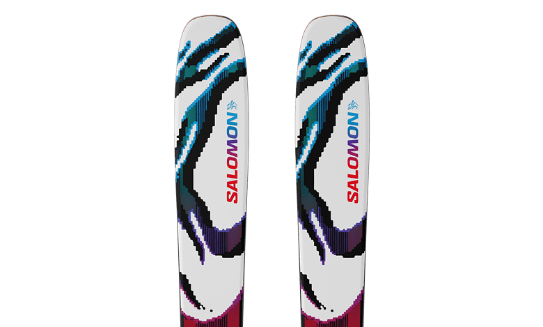 Pair of Salomon snow skis with vibrant, abstract design in blue, black, purple, and red on a white background, ideal for winter sports enthusiasts.