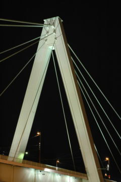 Stahlseilbrücke bei Nacht, modernes Design, ikonische Architektur, Wolfgang Kurtz, Lichtakzente, Hängebrücke, urbane Infrastruktur.