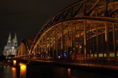 1. Moderne Brücke Köln nachts beleuchtet mit Dom im Hintergrund, spektakuläre Architektur und Lichterfassung.