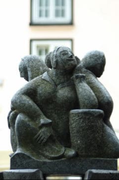 Fröhliche Skulptur in Stein, Künstler Wolfgang Kurtz, moderne Kunst, öffentliche Kunstinstallation, kreative Steinfigur auf Stadtplatz.