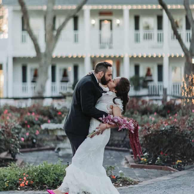 Groom Roble dipping bride Elaine for a kiss in front of House Estate mansion Houston Texas — multicultural wedding photographer Xiarm Films & Photography