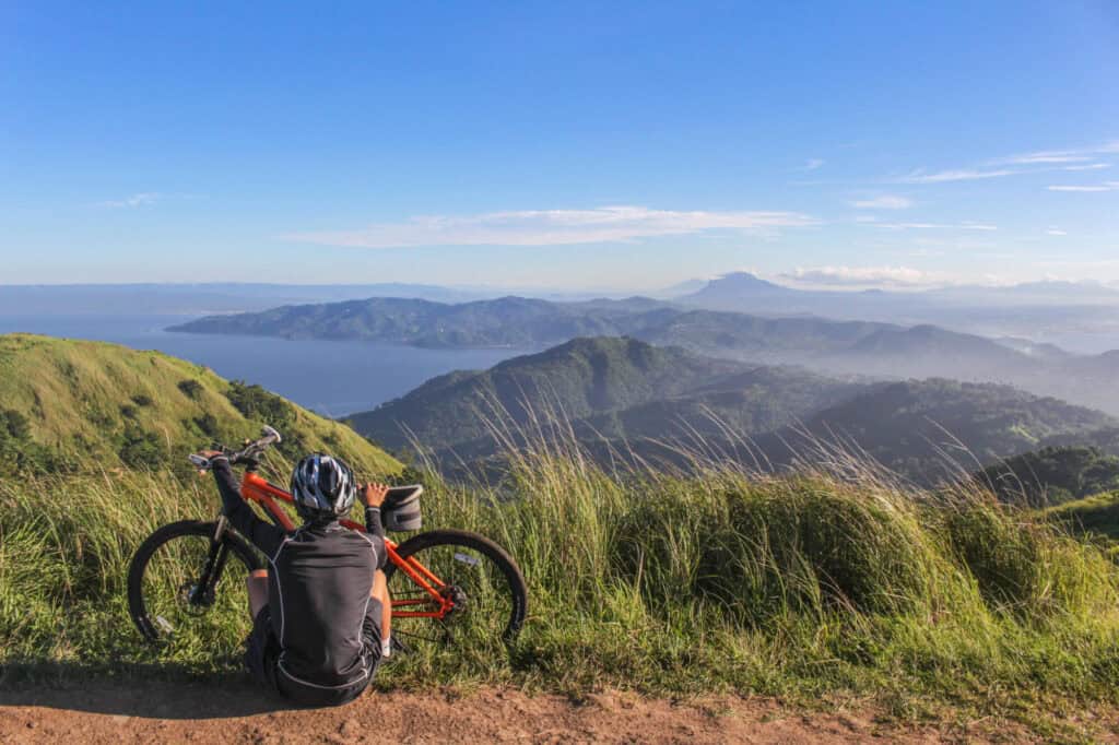 Mountainbike und Rucksack auf Bergpfad mit Blick auf Berge und Meer.