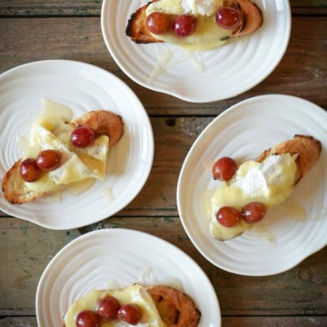 Four dishes each with one Grill Roasted Grape & Brie Crostini.