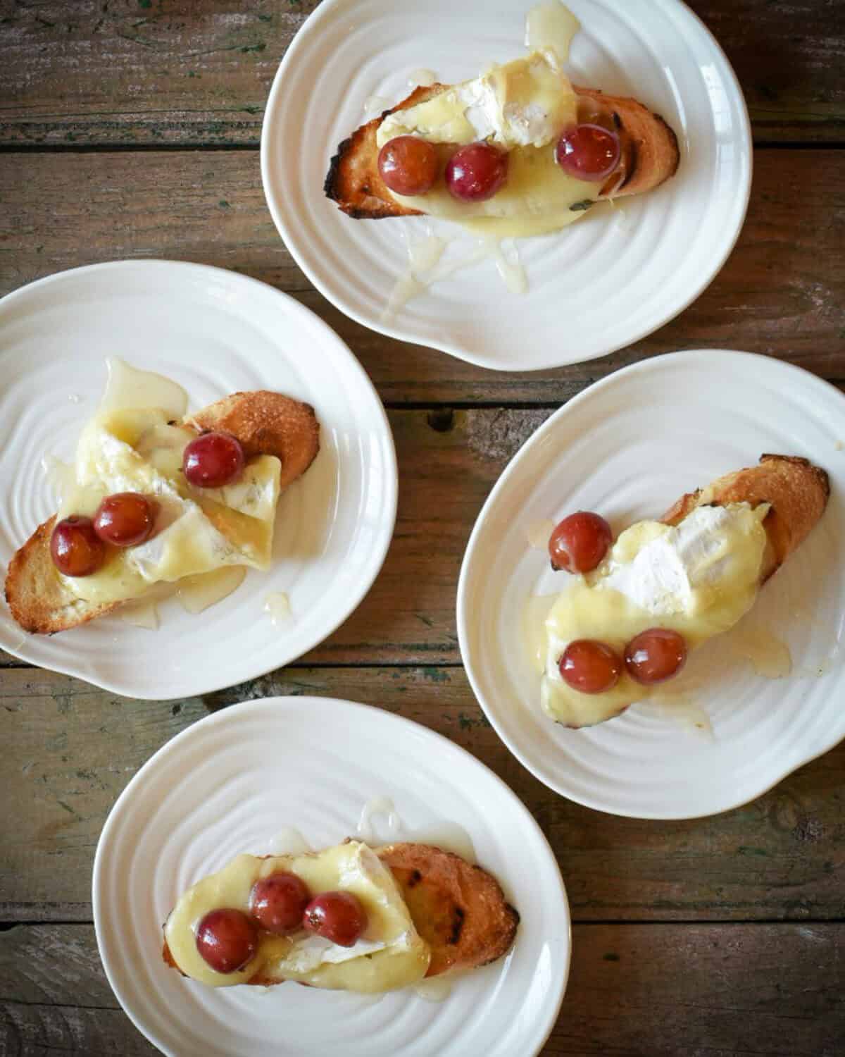 Four dishes each with one Grill Roasted Grape & Brie Crostini.