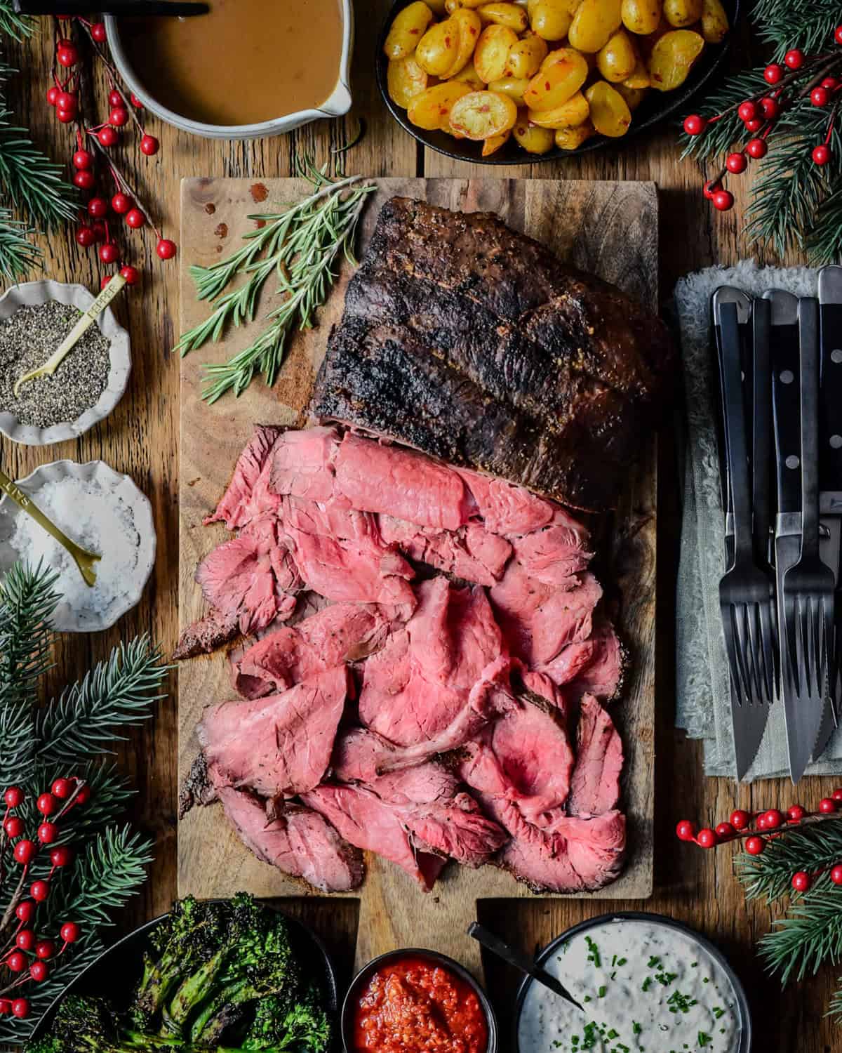 A grilled roast beef with half of it sliced thinly to reveal a perfect medium rare cook. Served with gravy, bomba potatoes and a horseradish cream sauce.