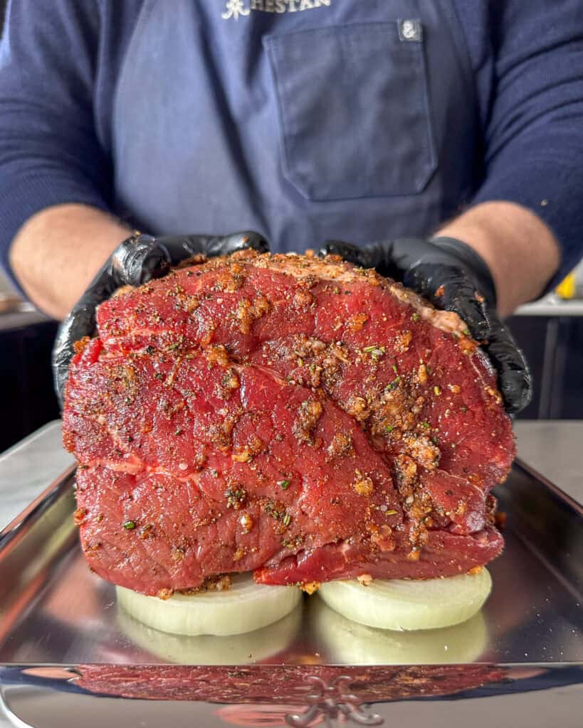 Season the beef and place on a bed of onions on a sheet pan.
