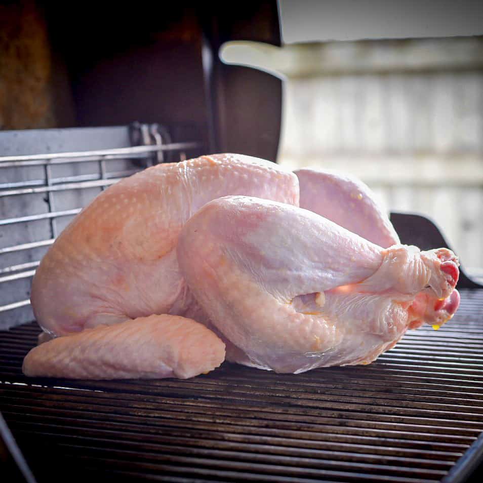 A raw turkey on the bbq grates about to be grilled.