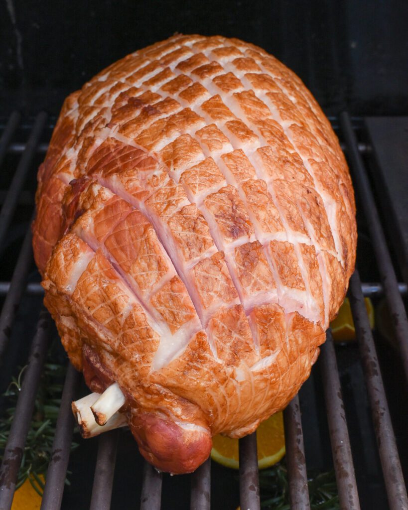 A ham on the grill scored in a crosshatch pattern.