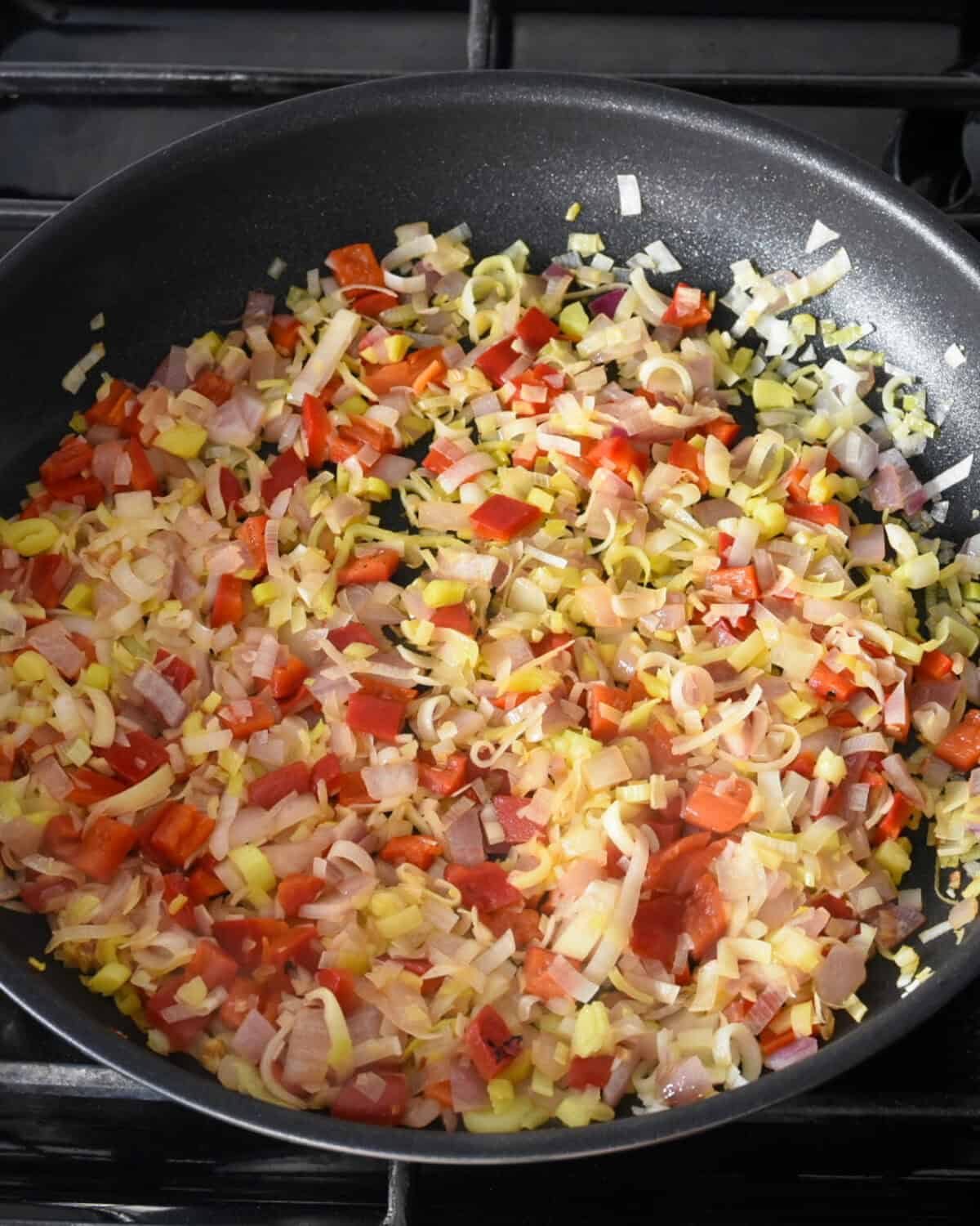 A pan of onions, leeks, and red peppers cooked until just soft,