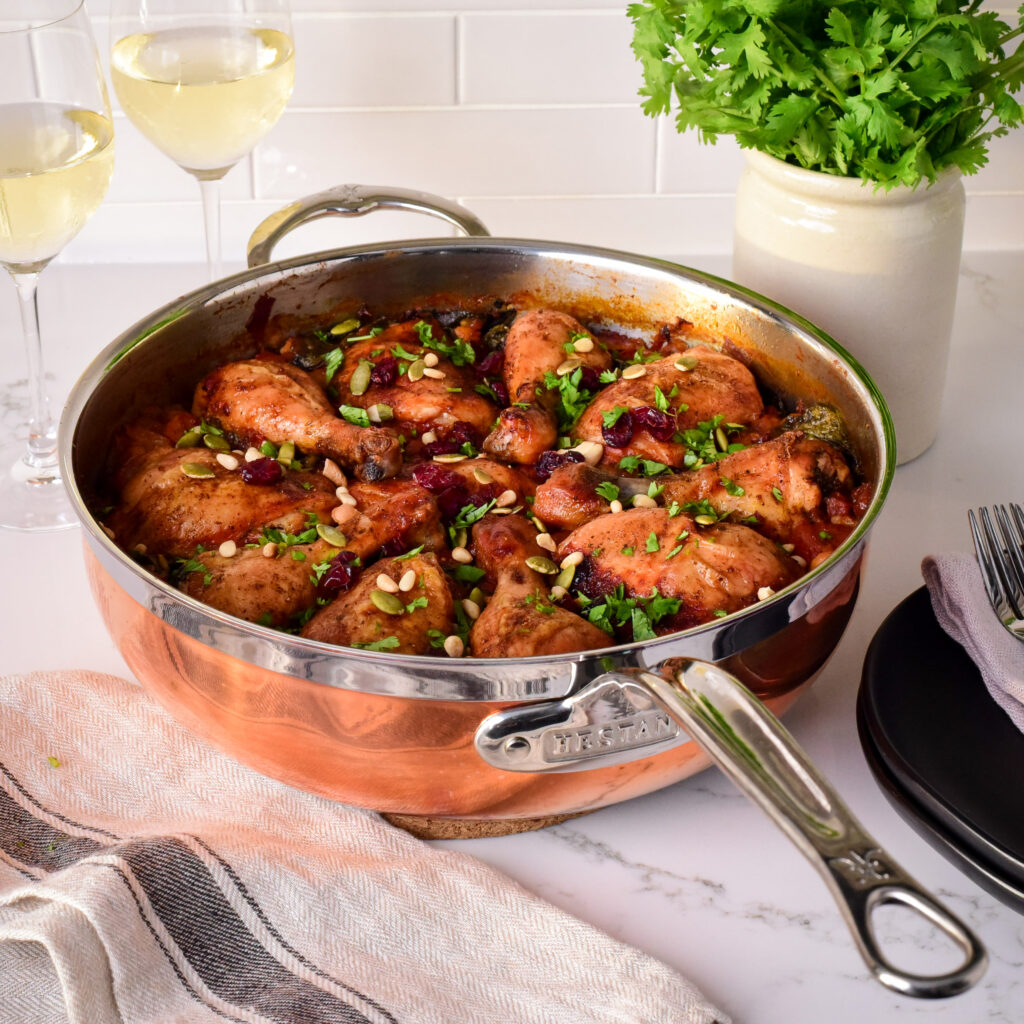 An image of a Moroccan inspired chicken and rice dish in a large copper pan.