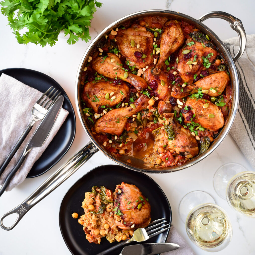 A Moroccan (Inspired) Chicken & Rice dish in a pan with a portion taken out onto a plate.