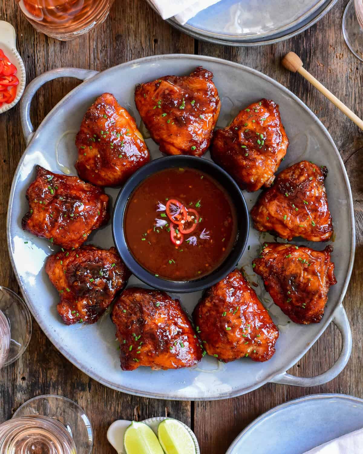 A platter with a ring of grilled chciken thighs with sauce in the middle.
