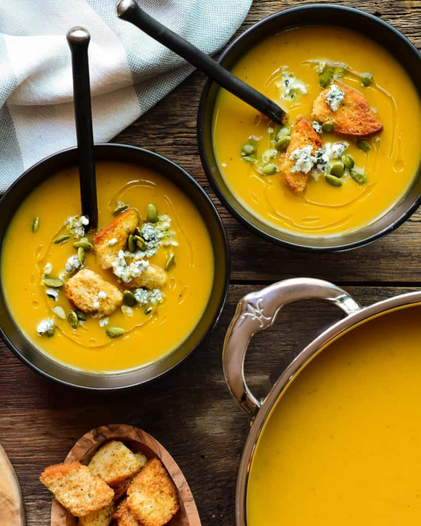 Two bowls and a pot of puréed roasted vegetable soup.