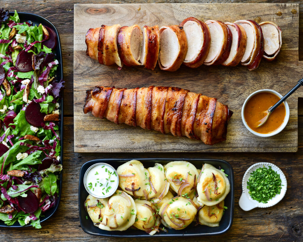 5 ingredient pork recipe. (One is sliced showing the juicy interior) A dish of pierogis and salad are also part of the meal.
