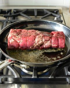 Browning the beef in a skillet with butter.