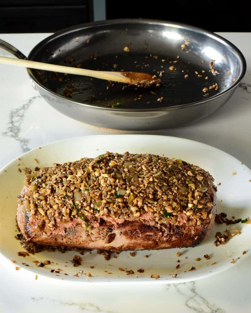 Top beef tenderloin with pâté slices and mushroom mixture.