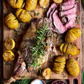 A sliced roasted leg of lamb with hasselback potatoes.