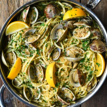 A finished pan of linguine and clams (Linguine alle Vongole) with lemons.