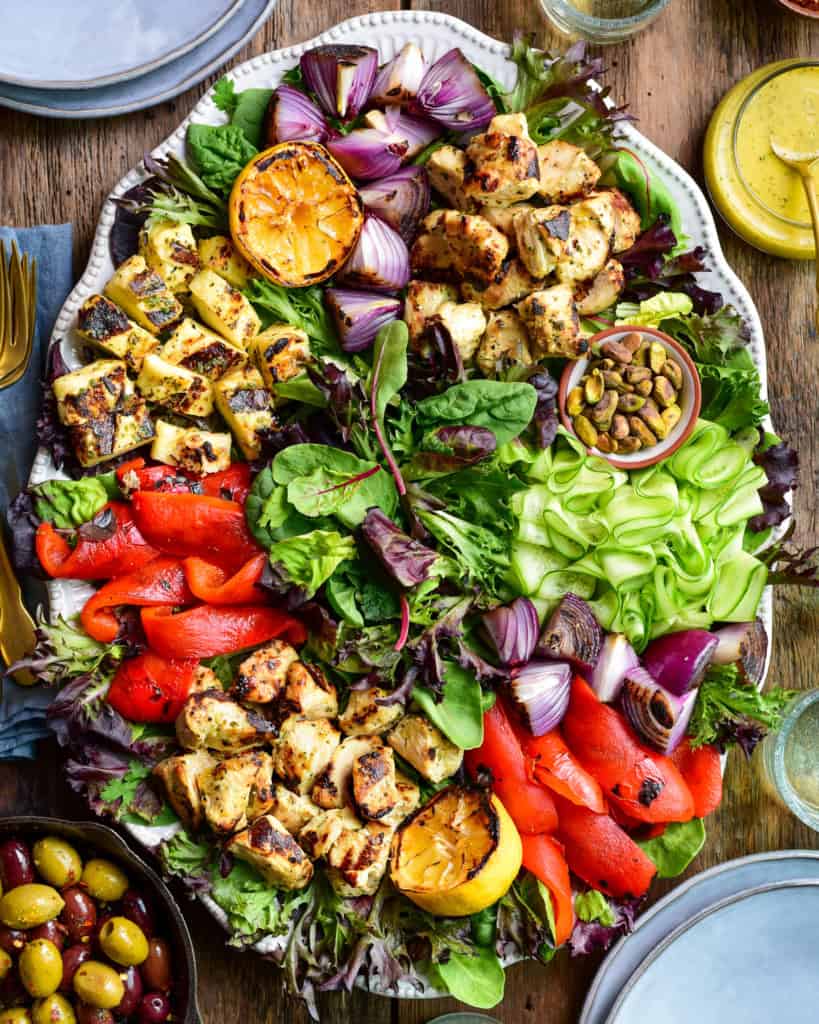 A grilled chicken and halloumi salad served with lemon dressing and olives.