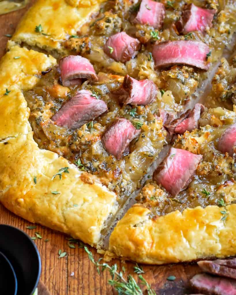 A close up of a steak and onion galette.