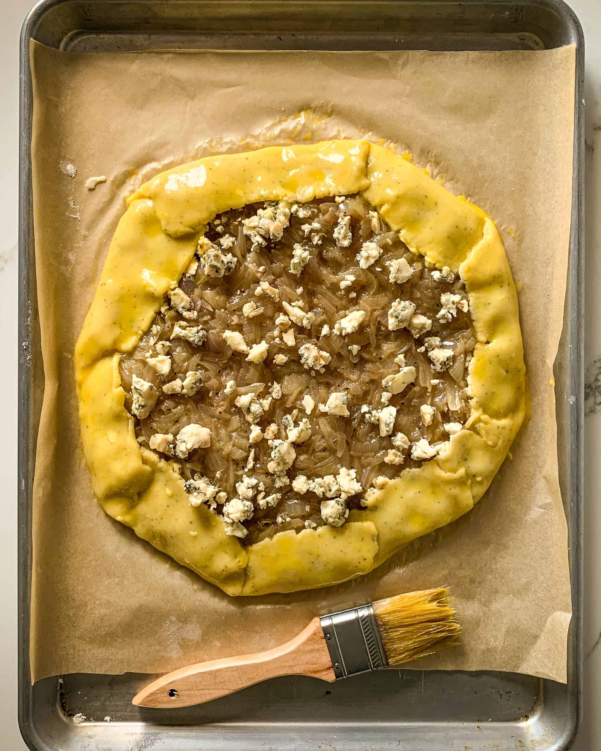 Steak & Onion Galette filled with onions and cheese, with brushed egg yolk edges.