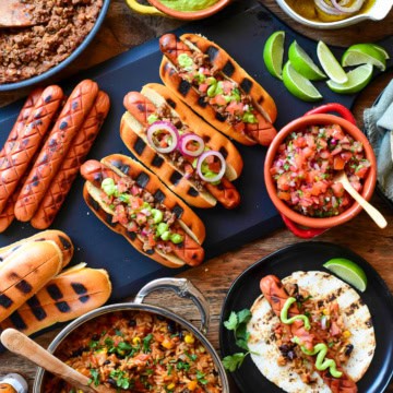 A spread of coney hot dogs with all the toppings.
