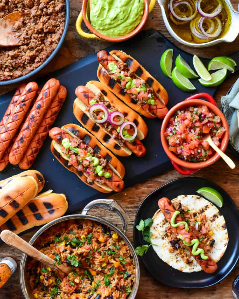 A spread of coney hot dogs with all the toppings.
