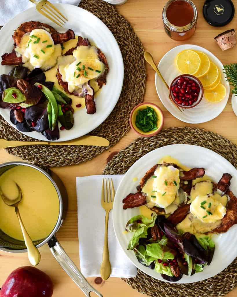 A top down image of two place settings of Eggs Benedict on Potato Pancakes