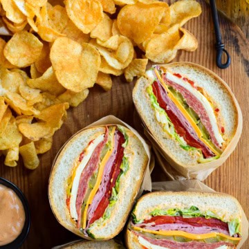 Stuffed sandwich halves reveal the layers of varieties of meat and cheese.