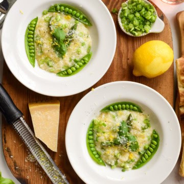 Two bowls of pea and asparagus risotto finished with basil, Parmesan and lemon.