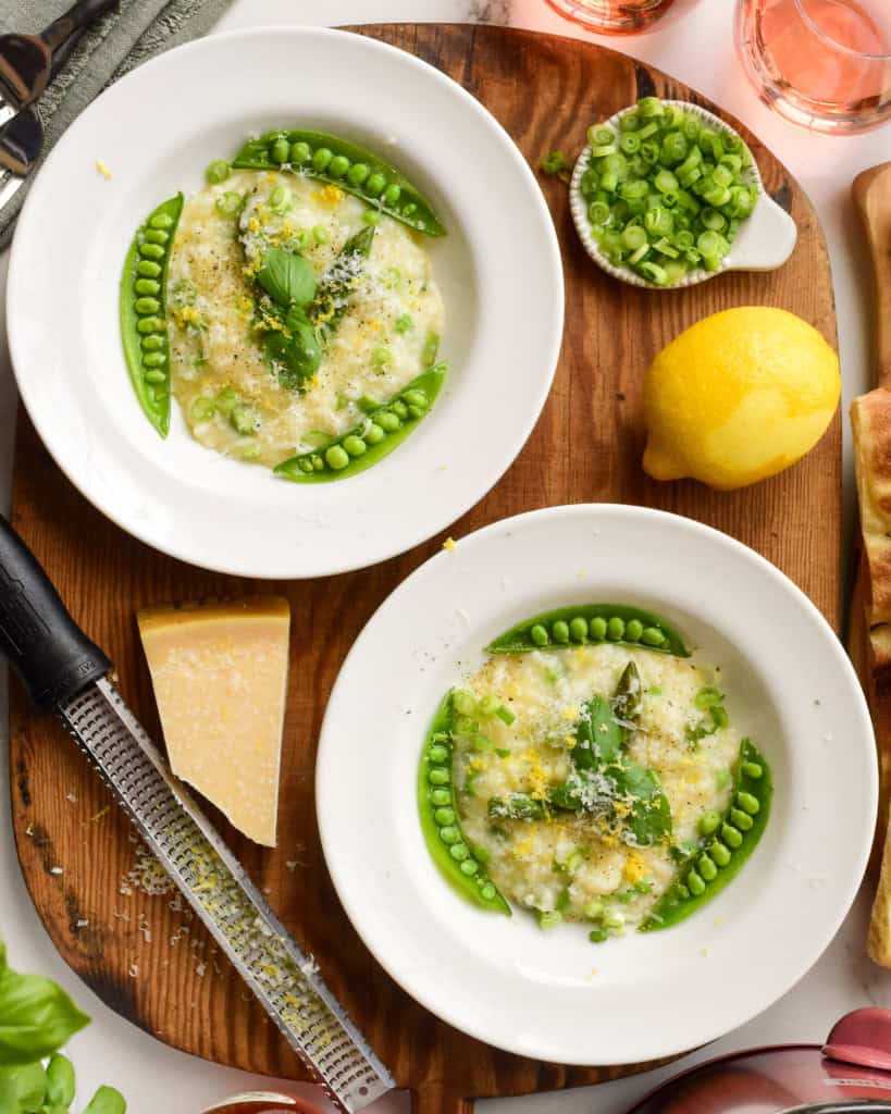 Two bowls of pea and asparagus risotto finished with basil, Parmesan and lemon.
