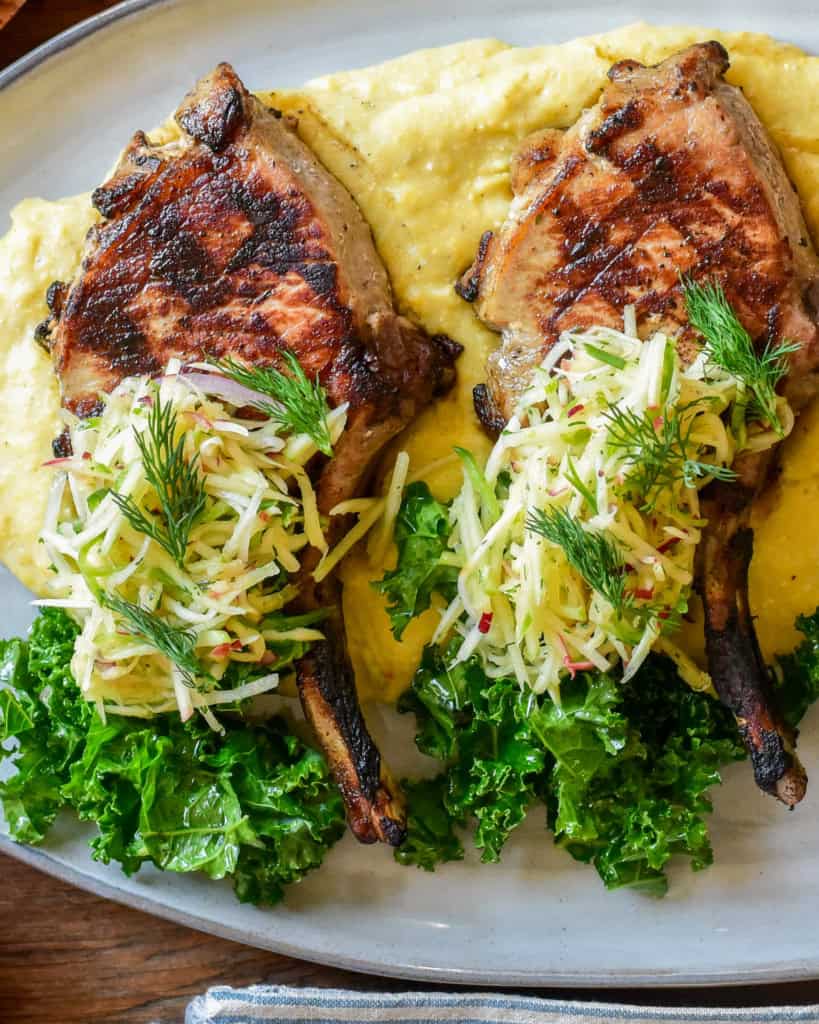 A pile of apple fennel slaw over two pork chops. 