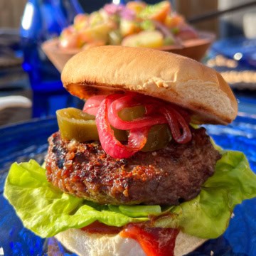 A beyond burger loaded with lettuce, sauce, pickles, jalapeños, sautéed onions on a bun.