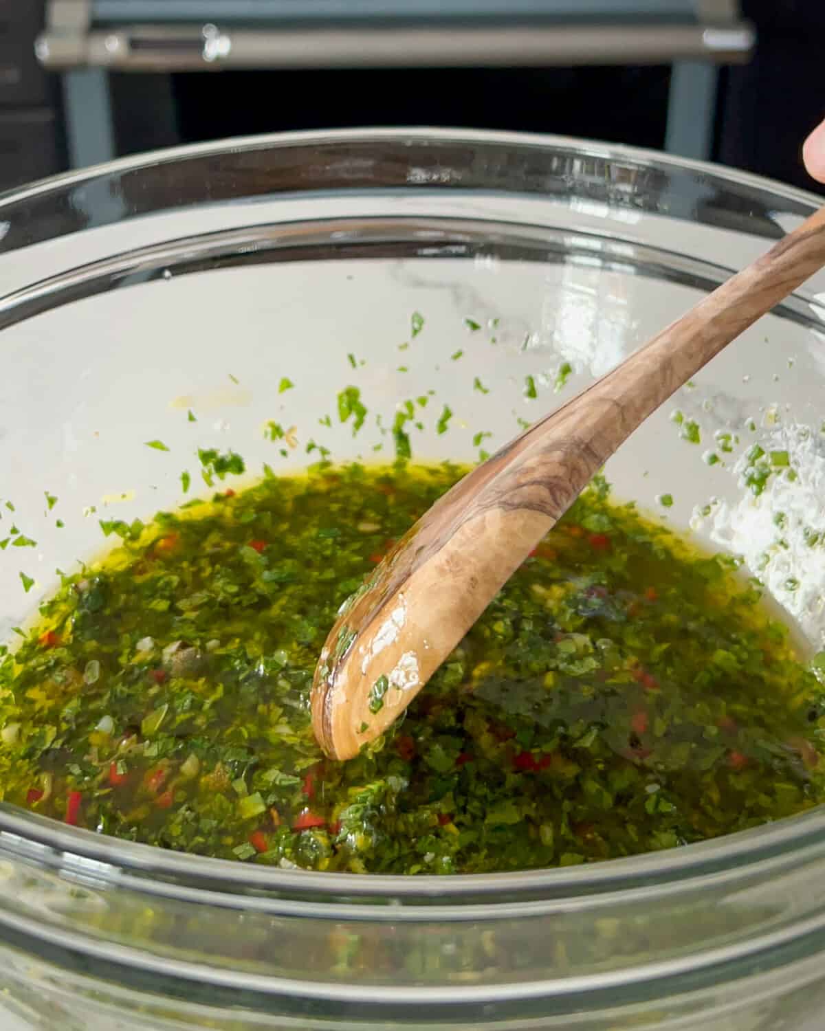 A bowl of salsa Verde with a wooden spoon.
