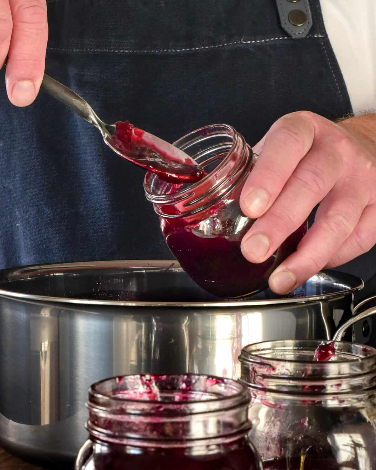 Spooning grape jam into jars.