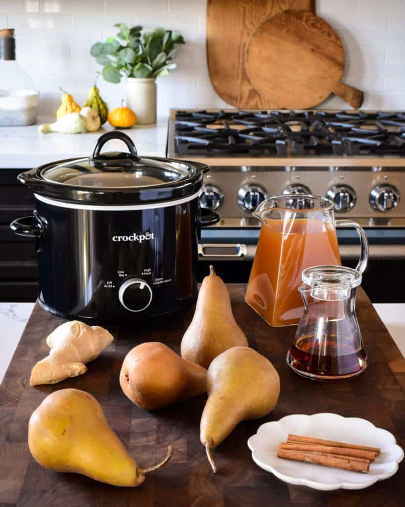 A small black Crockpot with ingredients to poach pears.