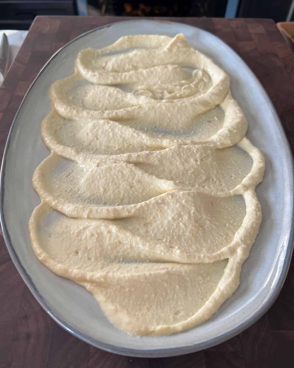 Wavy shmears of hummus on a platter.