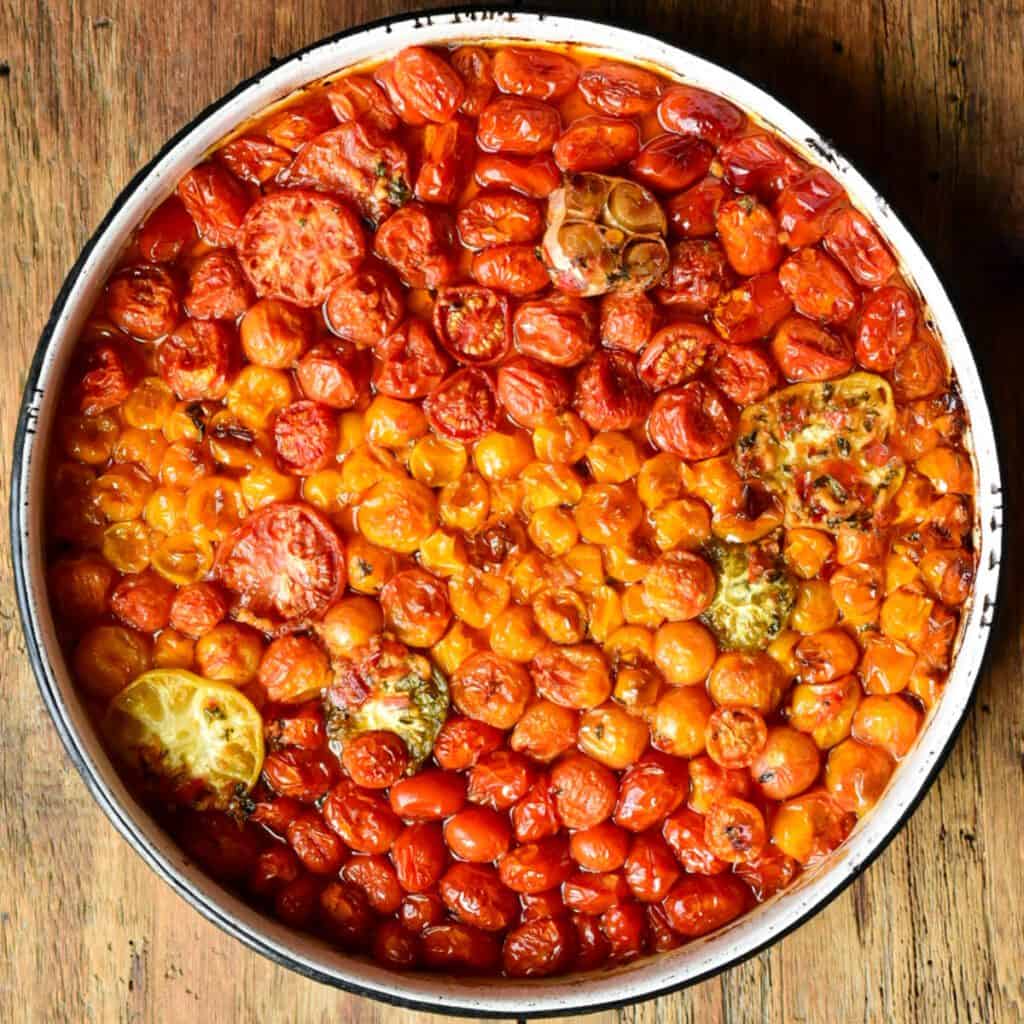 A round pan filled with cooked confit tomatoes and garlic.