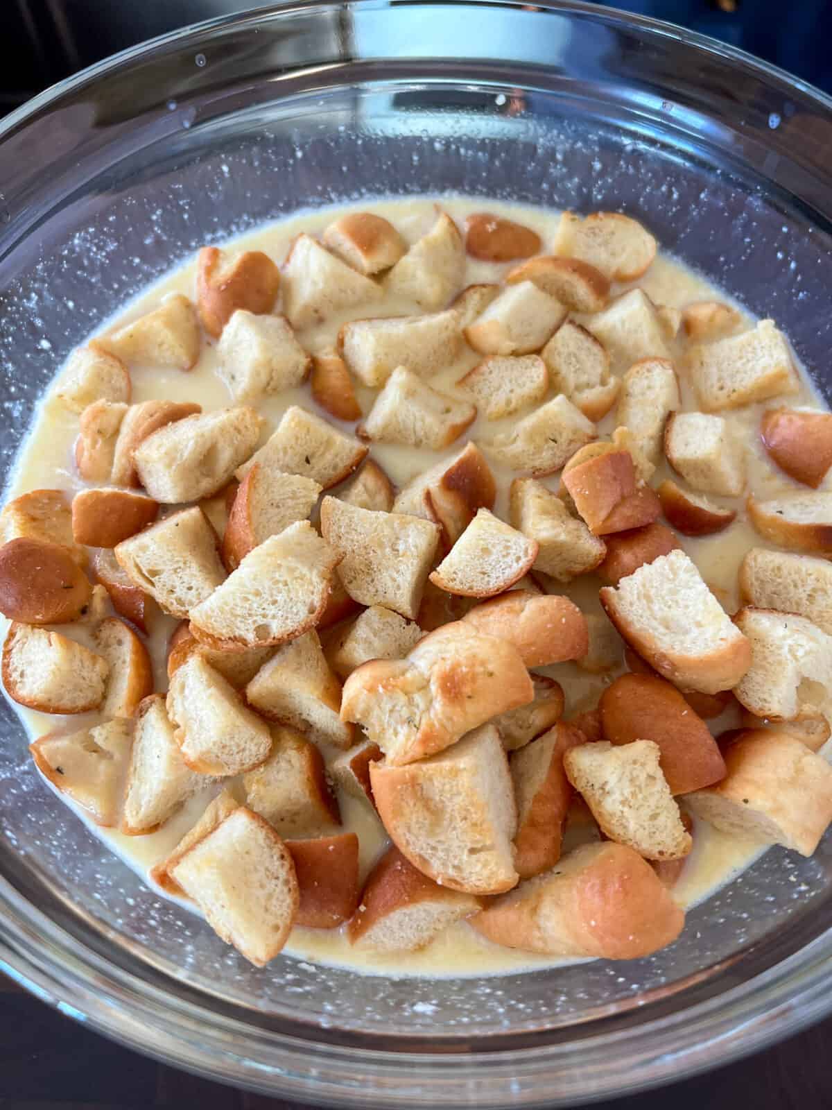 A mixture of eggs and cubed toasted bread in a bowl.