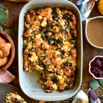 A retangular baking dish with a savoury bread pudding served with gravy and cranberries.
