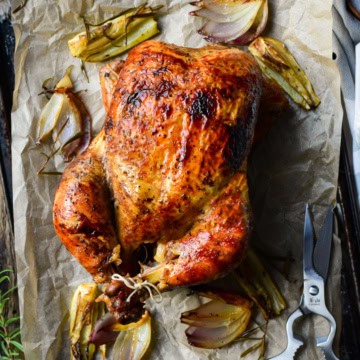A golden brown rotisserie chicken on a sheet pan.