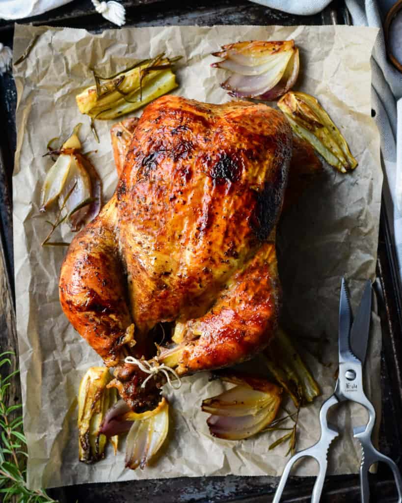 A golden brown rotisserie chicken on a sheet pan.