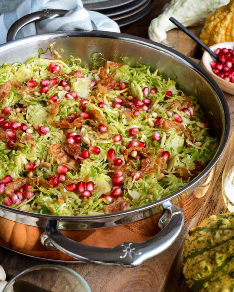 A copper pan with Shredded Brussels Sprouts with Pine Nuts, Pancetta and pomegranate arils.