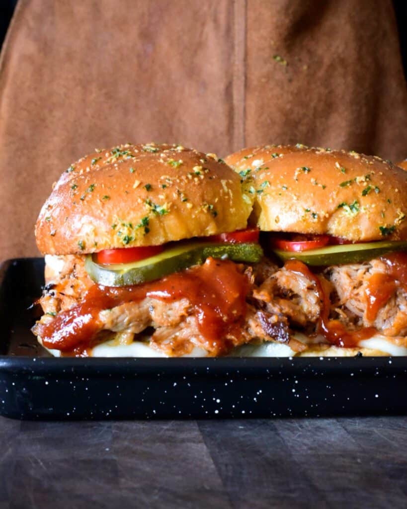 A side view of pulled pork sliders with BBQ sauce.